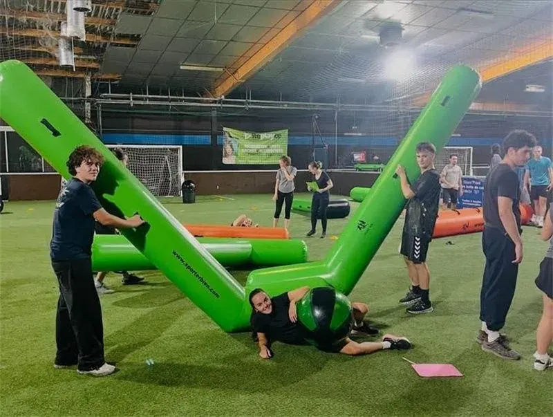 People beside oversized green inflatable hockey sticks at an indoor venue