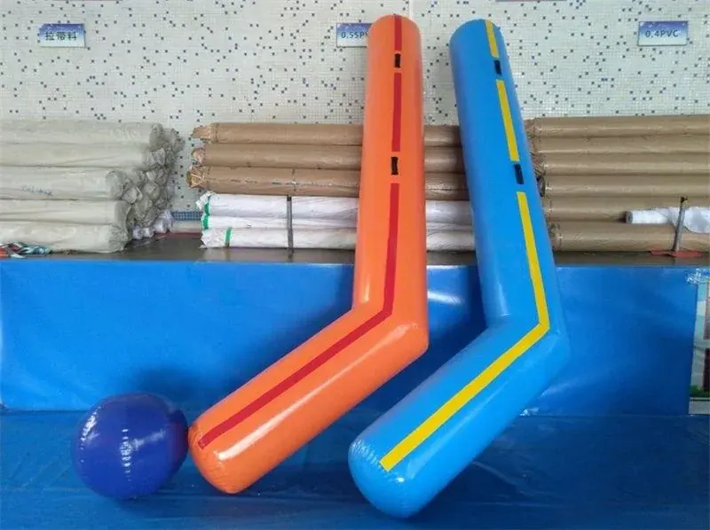 Two orange and blue oversized hockey sticks beside a purple ball